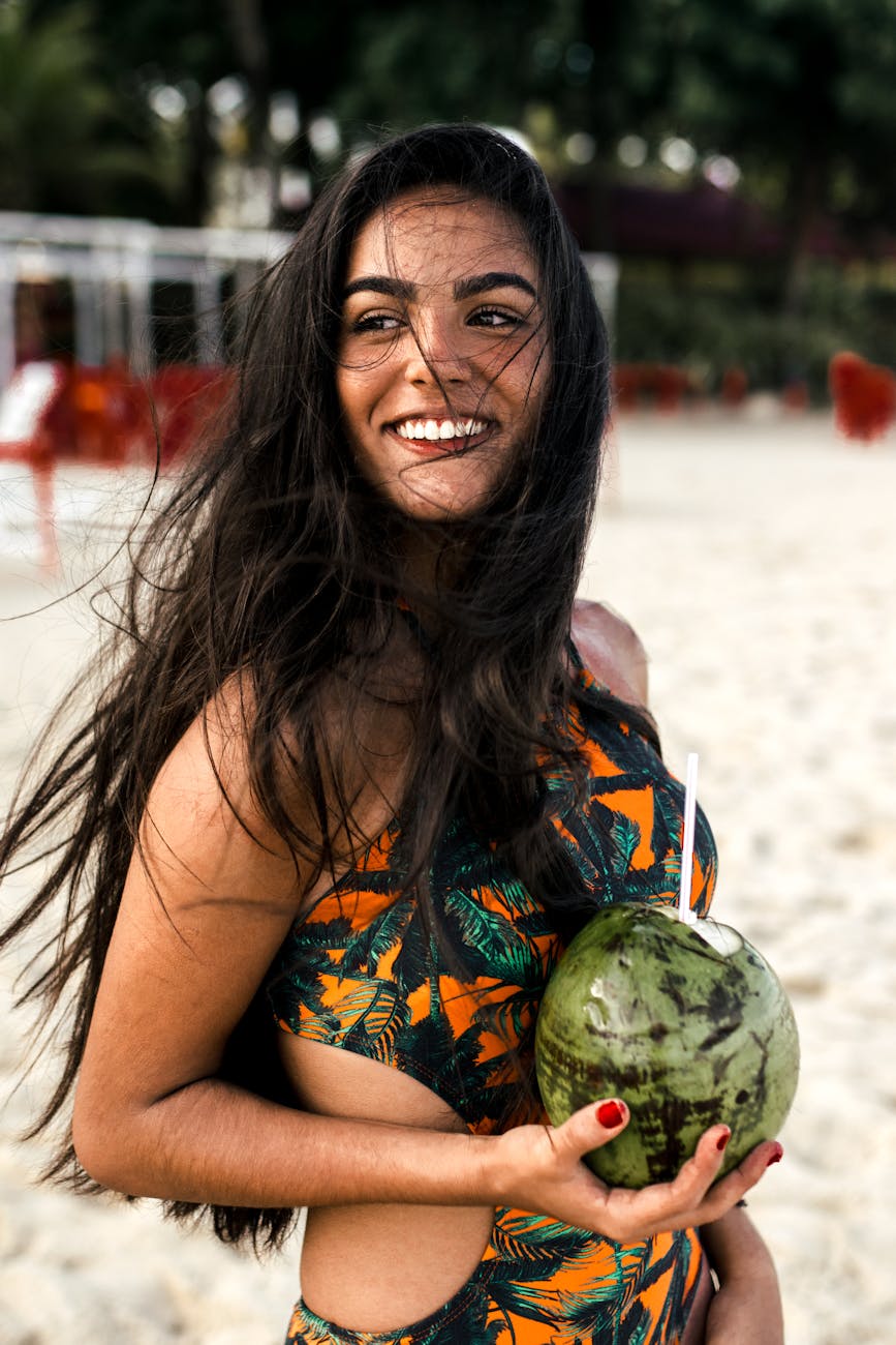 woman wearing black and yellow swimsuit carrying coconut fruit